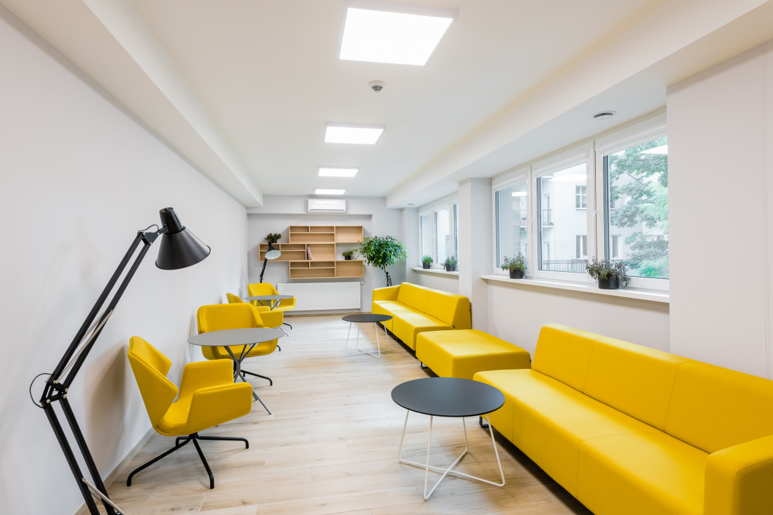 Widok pomieszczenia biurowego, rząd żółtych foteli oraz kanapy / sofy do siedzenia dla osób